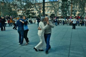 Parejas bailando tango con alegría durante el evento Tango con Ñ en Logroño, con público observando al fondo