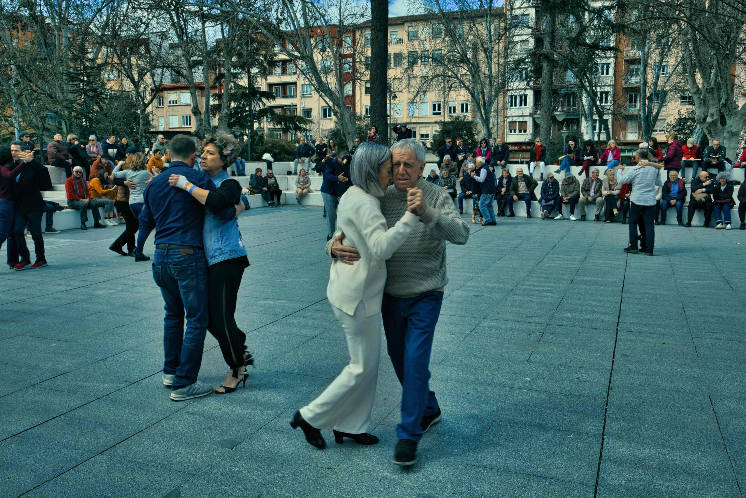 Parejas bailando tango con alegría durante el evento Tango con Ñ en Logroño, con público observando al fondo